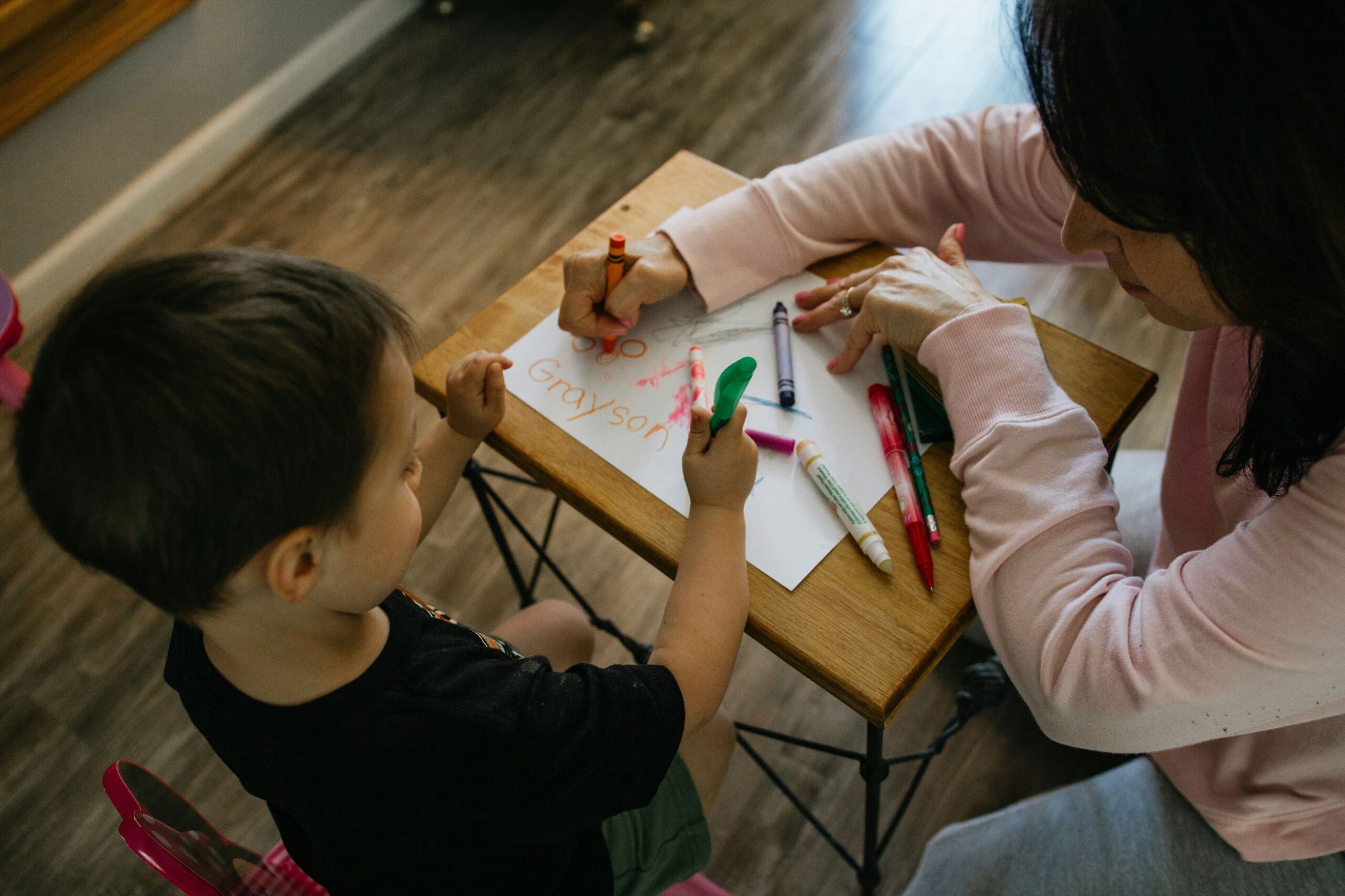 Toddler and adult practicing drawing letters
